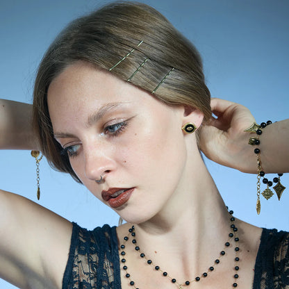Gold-tone Mirror Witness Stud Earrings worn in a downward-looking portrait with one hand positioned behind the head.
