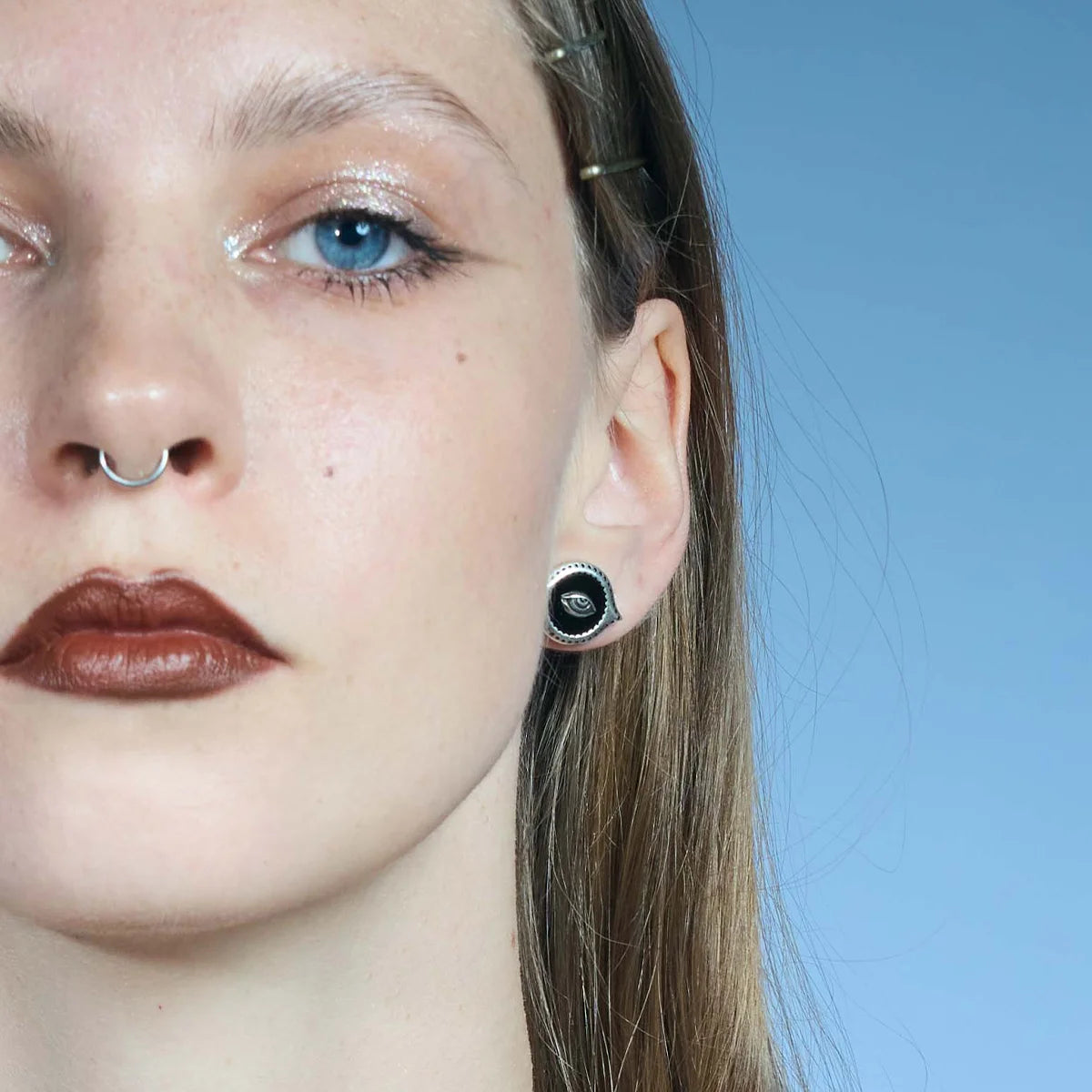 Front close-up of an antiqued silver-tone Mirror Witness Stud Earring with a raised eye motif over a black obsidian center.