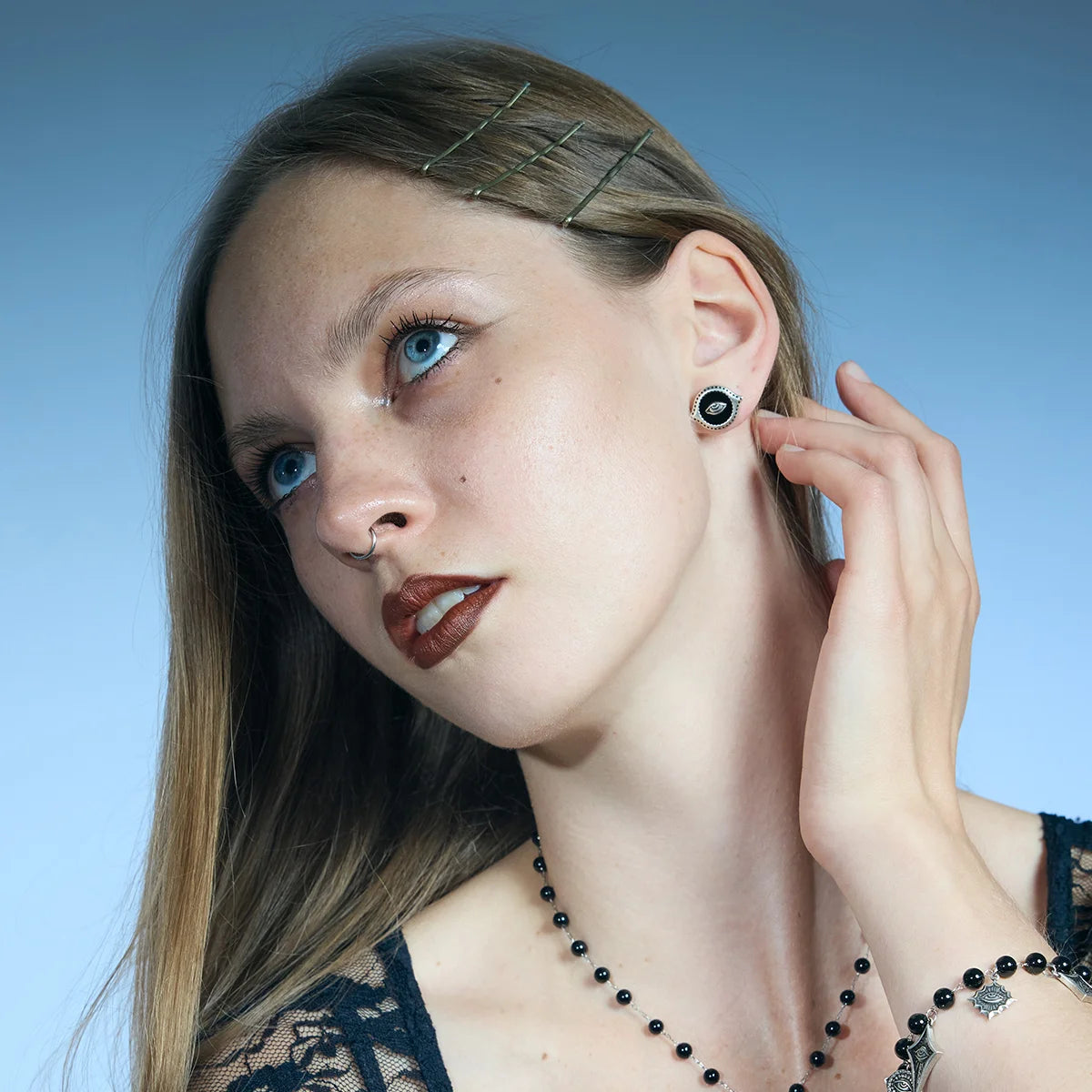 Antiqued silver-tone Mirror Witness Stud Earrings worn in a styled portrait with one hand raised near the ear.
