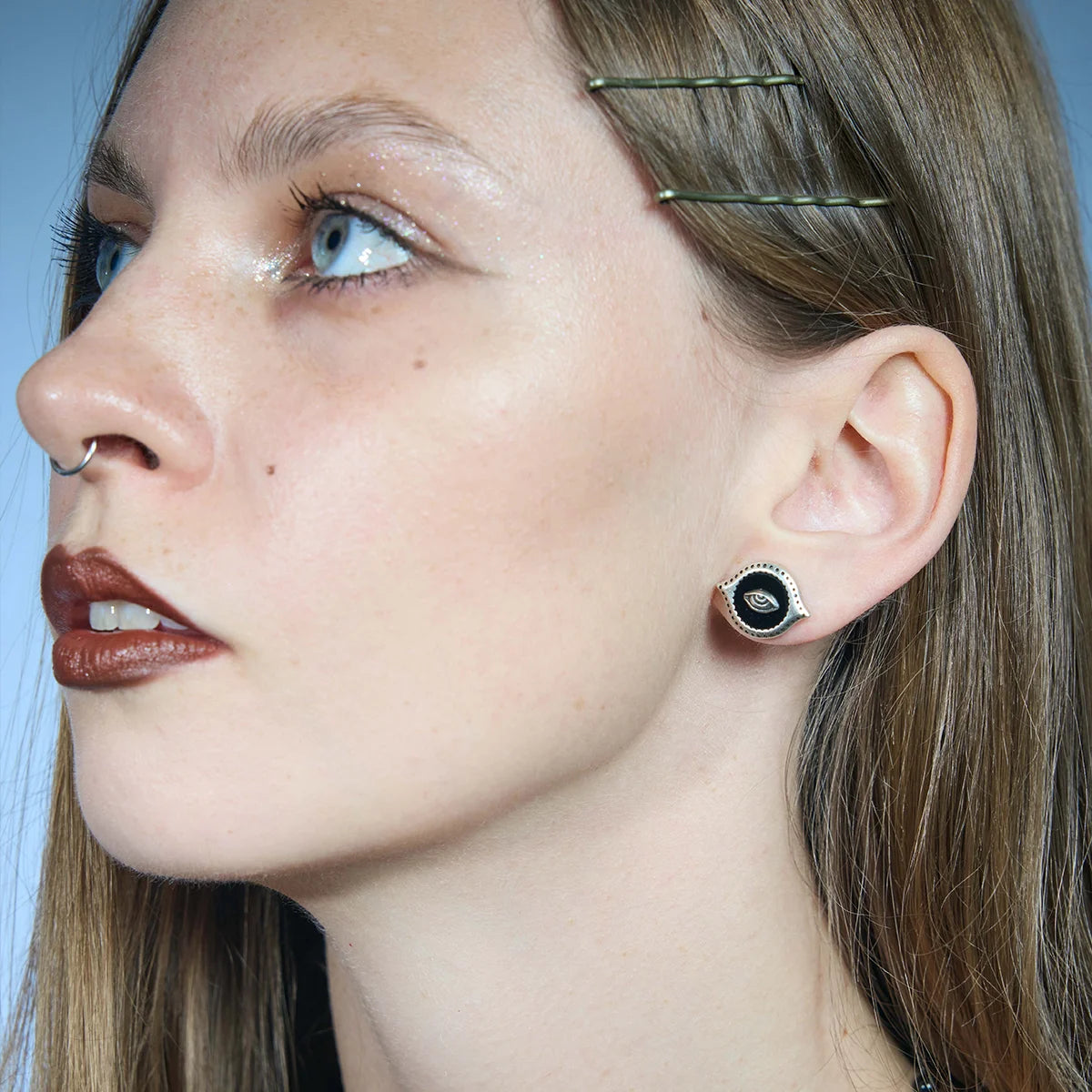 Three-quarter portrait showing an antiqued silver-tone Mirror Witness Stud Earring worn close to the lobe.