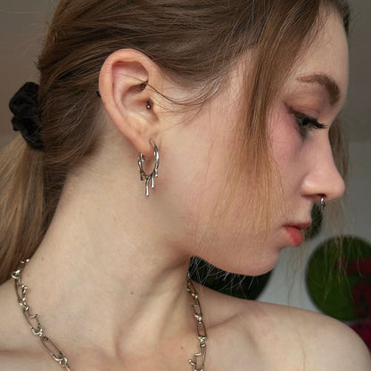 Molten Drop Earrings in 925 sterling silver, worn in side profile with brown hair tied back and a silver chain necklace.