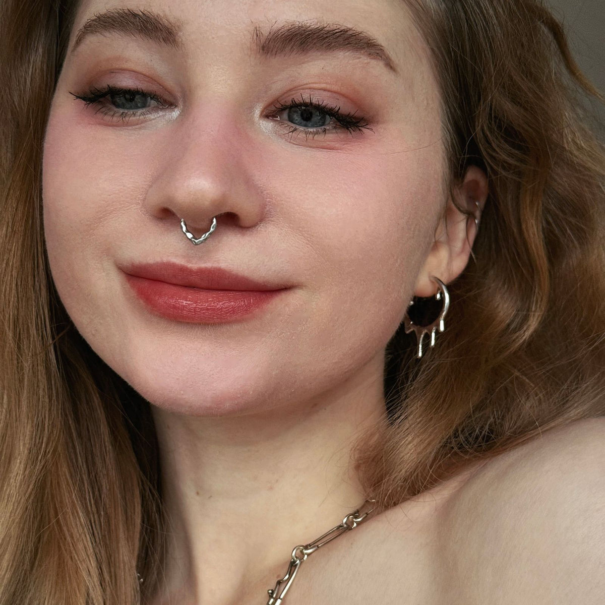 Molten Drop Earrings in 925 sterling silver, worn in a front-facing selfie with red hair, a septum ring, and layered silver j