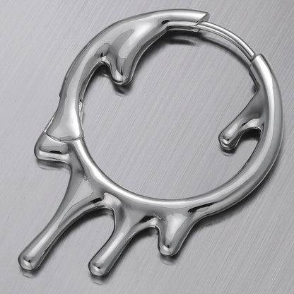 Close-up of a silver-tone hoop earring with a melted drip design resting on a metal surface