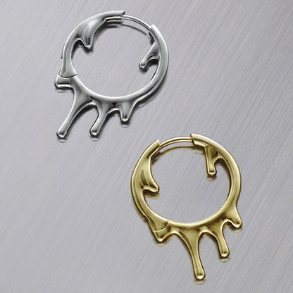 Silver-tone and gold-tone drip hoop earrings laid flat side by side on a brushed metal surface