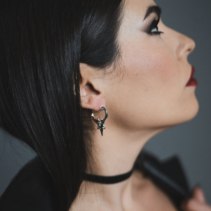 Side view of model wearing a silver Mystic Crest heart hoop earring