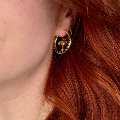 Close-up of gold Mystic Fungi hoop earring worn on the earlobe