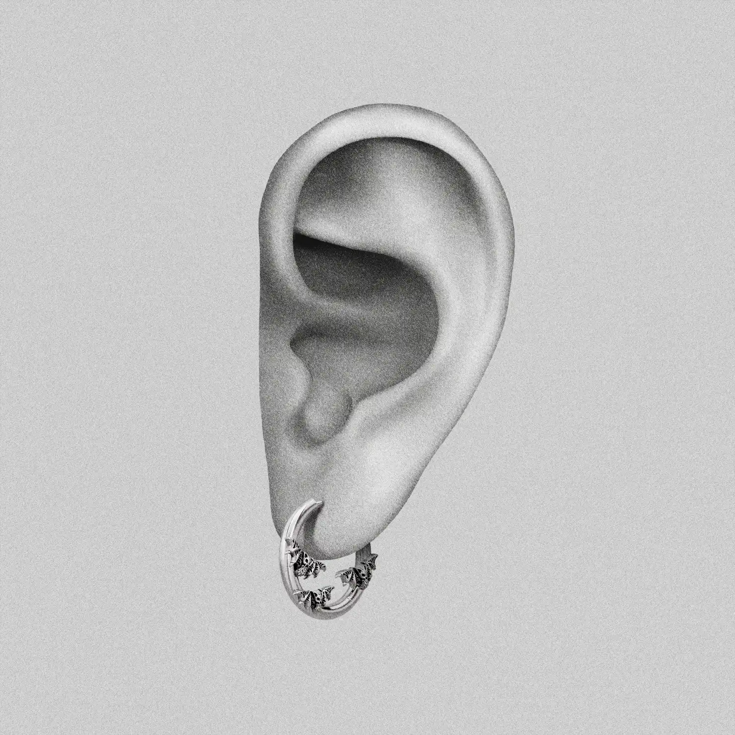 Silver Mystic Insight hoop earring with small bat details shown on an ear illustration