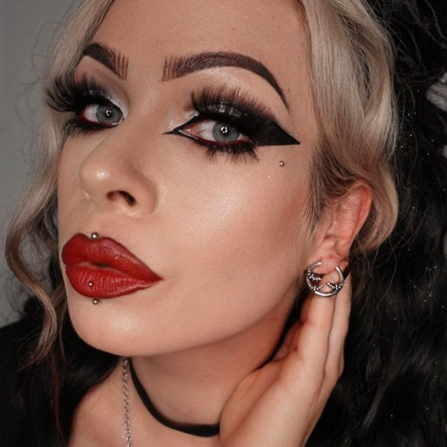 Model with dramatic makeup wears a silver-tone crescent hoop earring with bat detailing