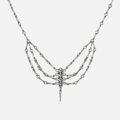 Silver-tone spine necklace with layered chains and a spike pendant, shown flat on a plain background