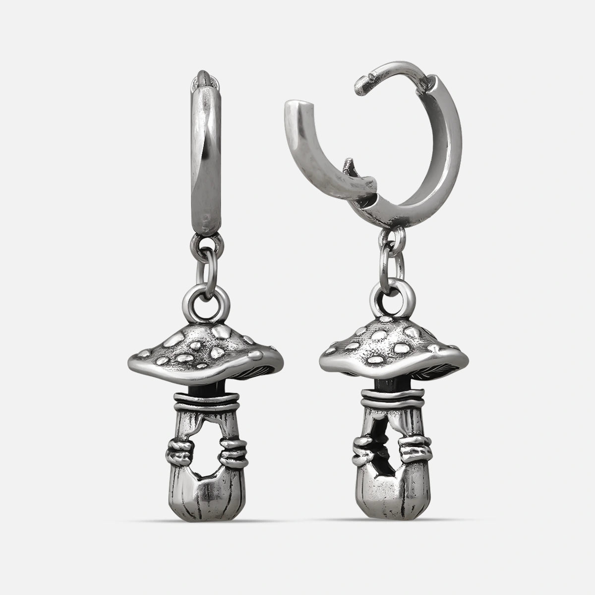 Silver-tone huggie hoop earrings with dangling textured mushroom charms, shown as a matching pair