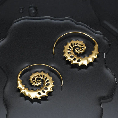 Gold Nautilus Omen Earrings displayed on a dark wet surface, featuring spiral shell shapes, cutout ridges, and coastal gothic styling.