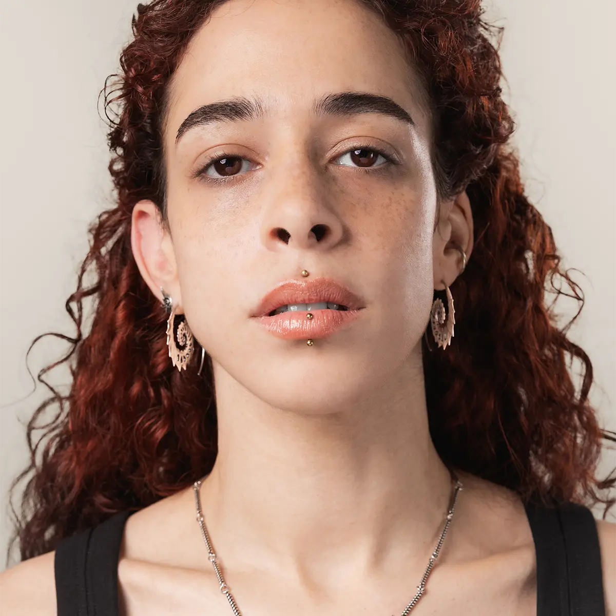 Model wearing the gold Nautilus Omen Earrings, showing the ancient spiral shell shape and dark coastal gothic mood.