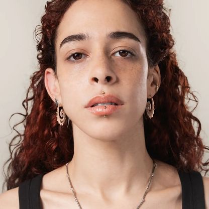 Model wearing the gold Nautilus Omen Earrings, showing the ancient spiral shell shape and dark coastal gothic mood.