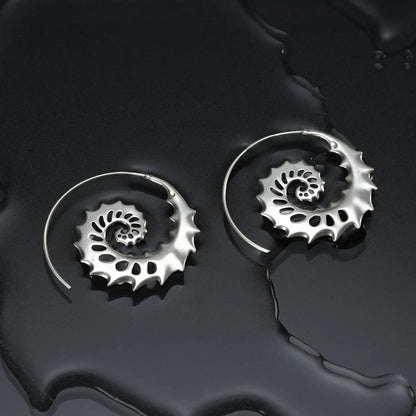 Silver Nautilus Omen Earrings displayed on a dark wet surface, highlighting the spiral shell shape and sea-worn gothic silhouette.