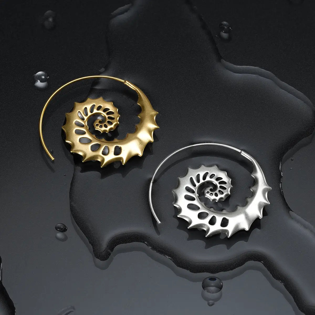 Silver and gold Nautilus Omen Earrings displayed on a dark wet surface, showing the spiral shell forms and dark ocean relic mood.