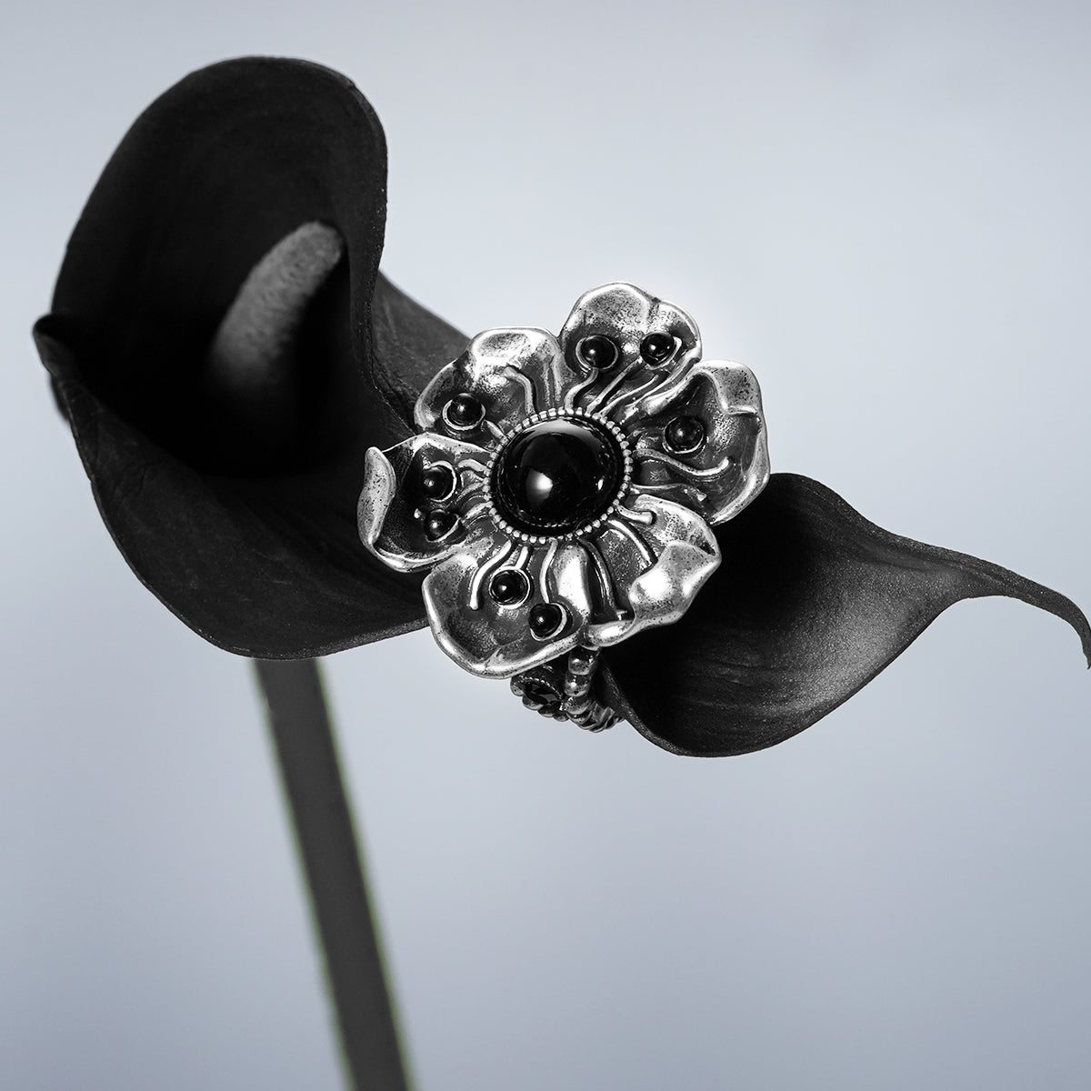 Silver Nocturne Bloom ring with black-centered flower displayed on dark fabric