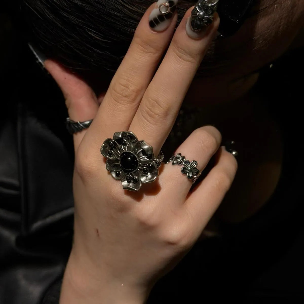 Model wearing the silver Nocturne Bloom Ring with black obsidian center, weathered floral petals, and dark gothic ring styling.