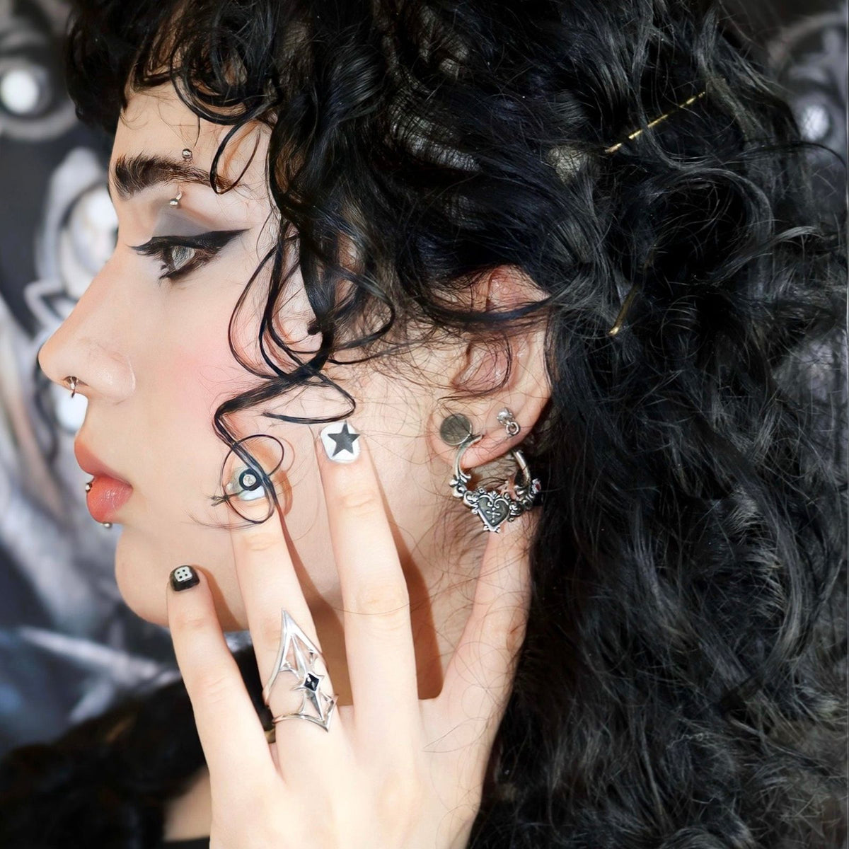Ornate Affection Earrings in 925 sterling silver, styled on a curly-haired model with facial stickers, stacked silver earring