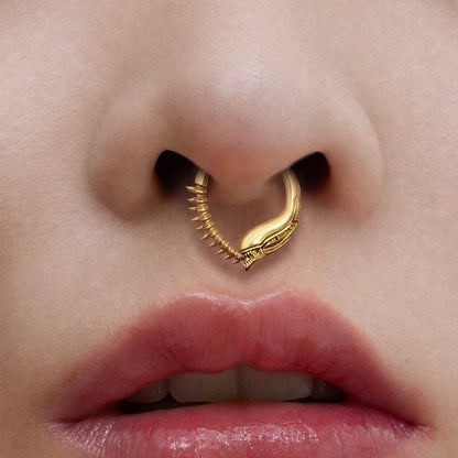Gold-tone Ouroboros Clicker worn as a septum ring, showing its curved serpent-inspired design.