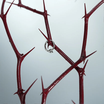 Pair of silver Ouroboros Coil clickers hanging from red thorn branches