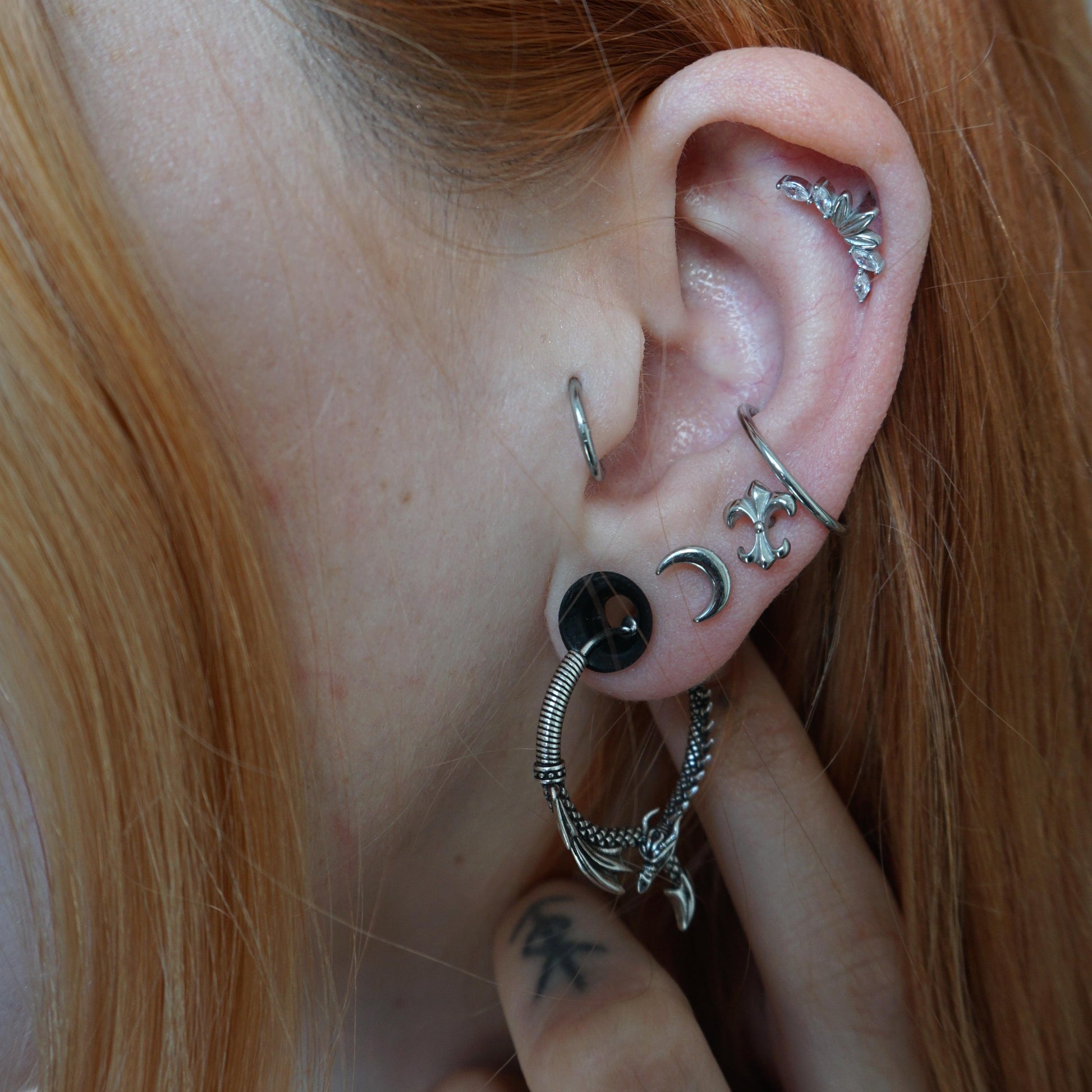 Close-up of silver Ouroboros Dragon earring worn with multiple ear piercings