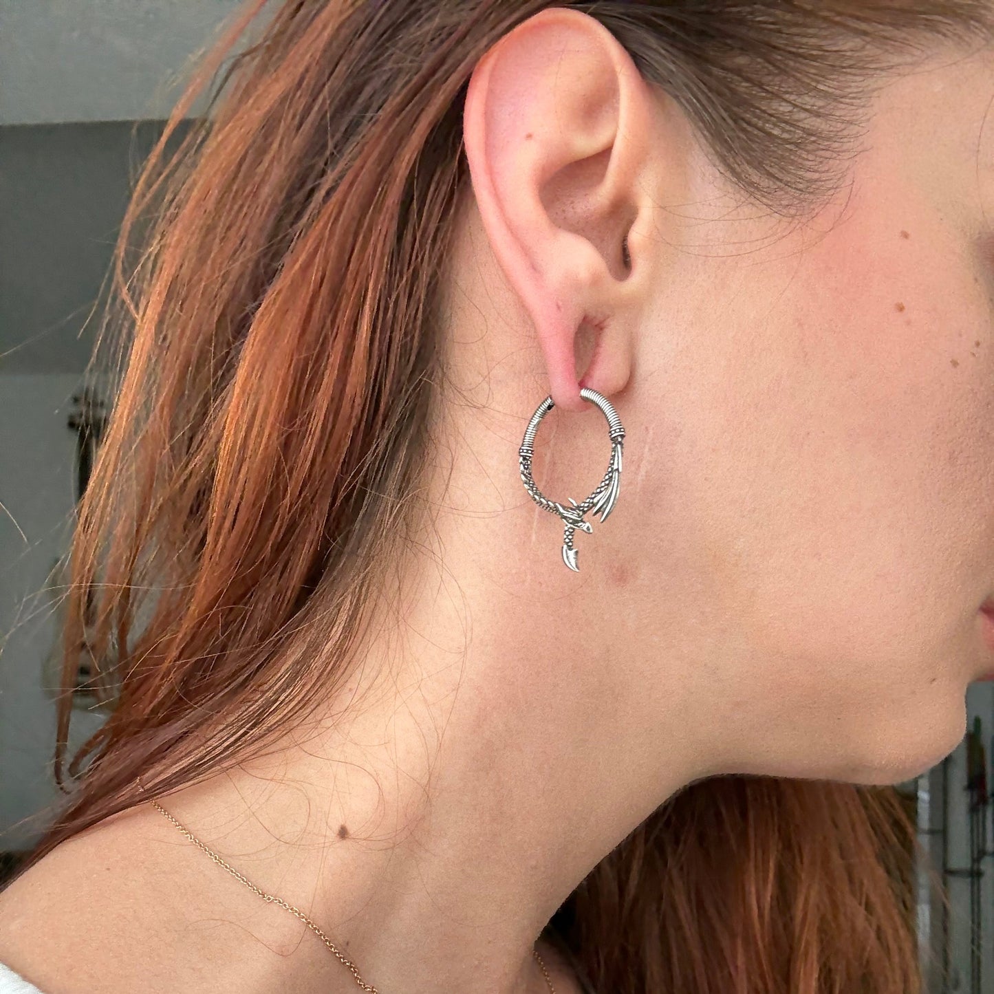 Side view of silver Ouroboros Dragon hoop earring worn on the earlobe