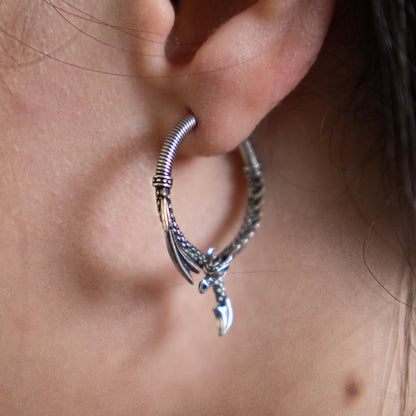 Silver-tone dragon hoop earring worn in a close-up view of a model's ear
