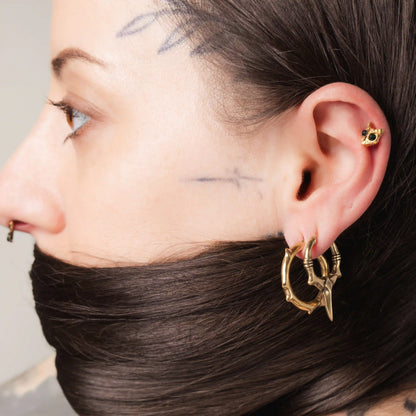 Model wearing gold Owl Skull Ear Studs with obsidian eyes and woodland gothic styling