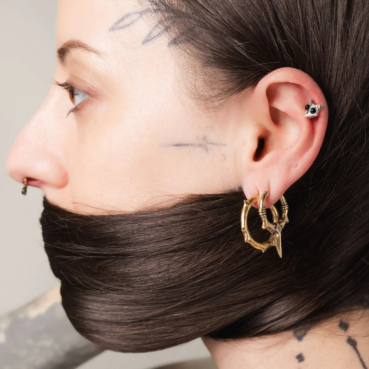 Model wearing silver Owl Skull Ear Studs with black obsidian eyes and sharp owl skull detail