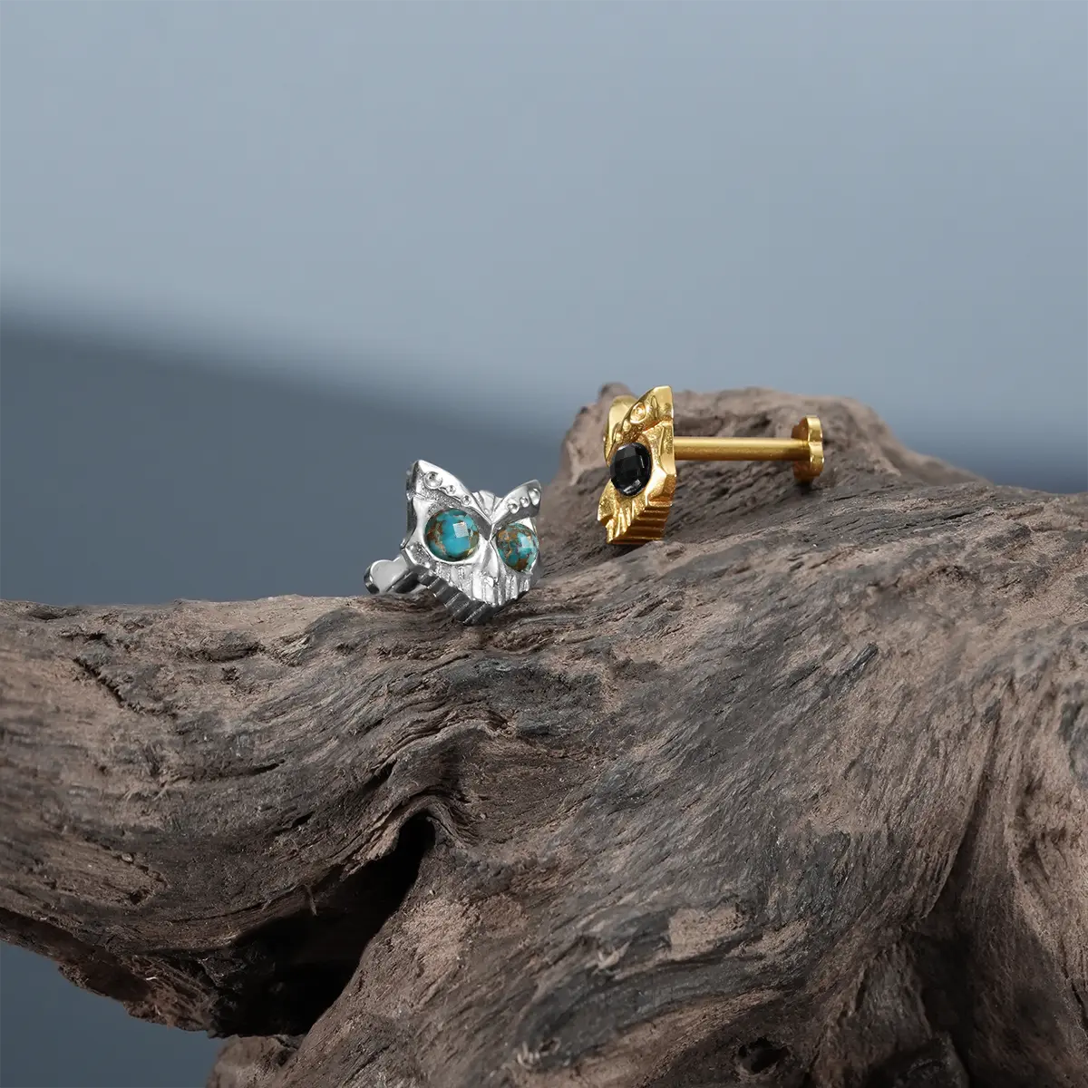 Silver Owl Skull Ear Studs shown from side on driftwood with titanium post backing