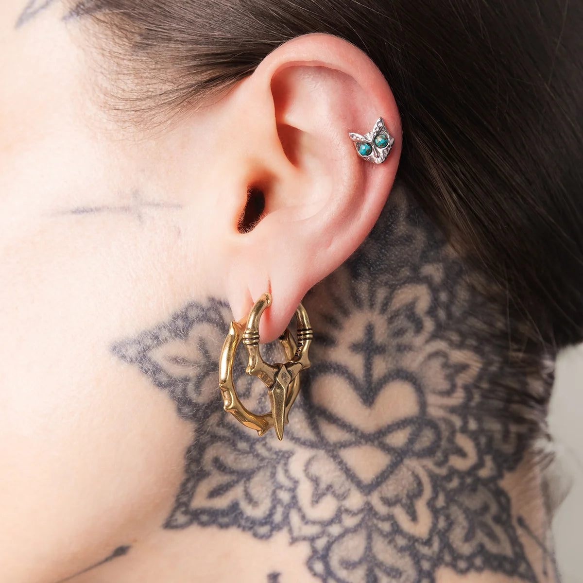 Model wearing silver Owl Skull Ear Studs with turquoise eyes and gothic owl jewelry styling