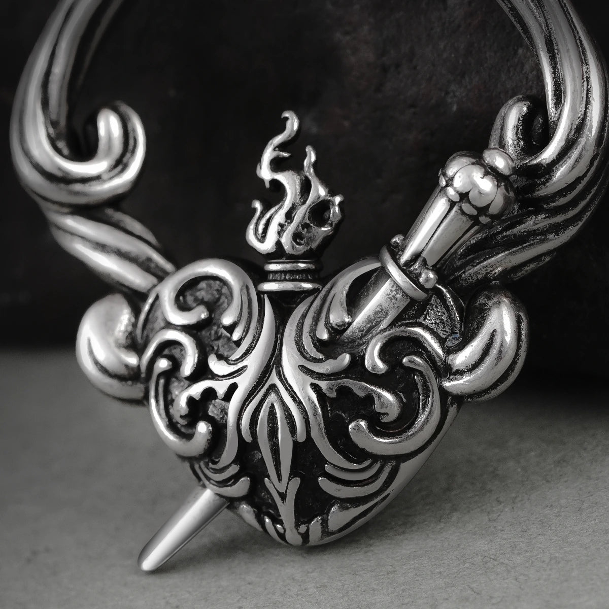 Close-up of silver Passionate Heart earring with flame and scroll details