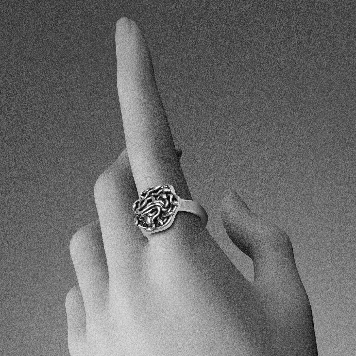 petrified gaze rings in silver shown on hand, featuring a medusa-inspired face surrounded by sculpted snake details