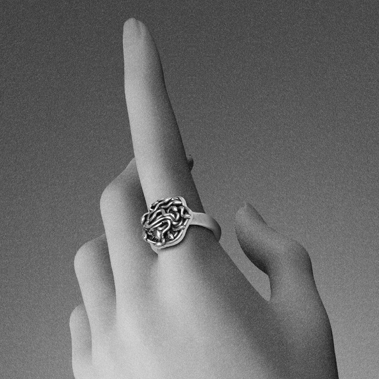 petrified gaze rings in silver shown on hand, featuring a medusa-inspired face surrounded by sculpted snake details