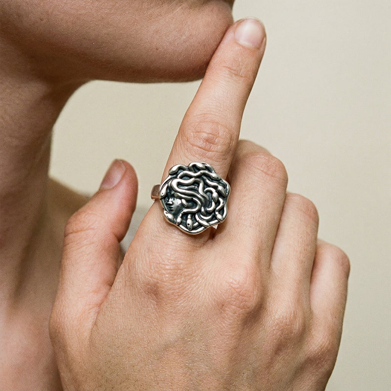 model wearing petrified gaze rings in silver, featuring a medusa-inspired face surrounded by sculpted snake details