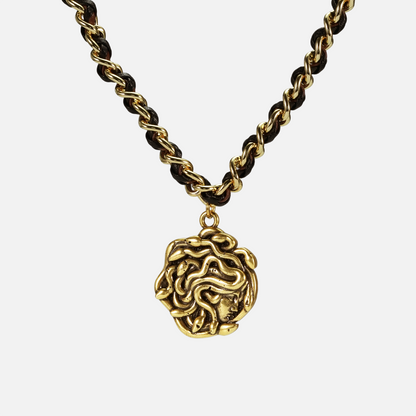 petrified power necklace in gold shown in a front close-up view, featuring a medusa-inspired pendant on a braided chain
