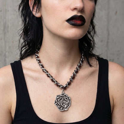 model wearing petrified power necklace in silver, featuring a medusa-inspired pendant on a mixed-chain necklace