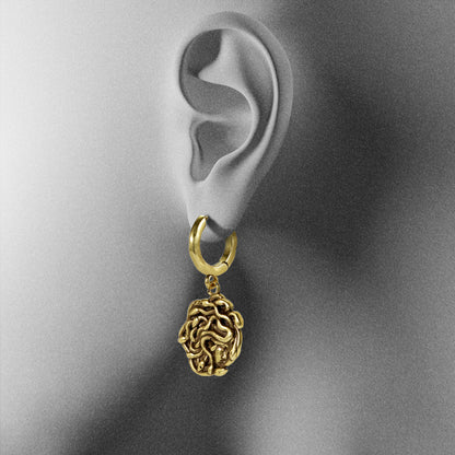 gold petrifying gaze dangle earrings shown on an ear display, featuring a medusa-inspired charm suspended from a hoop