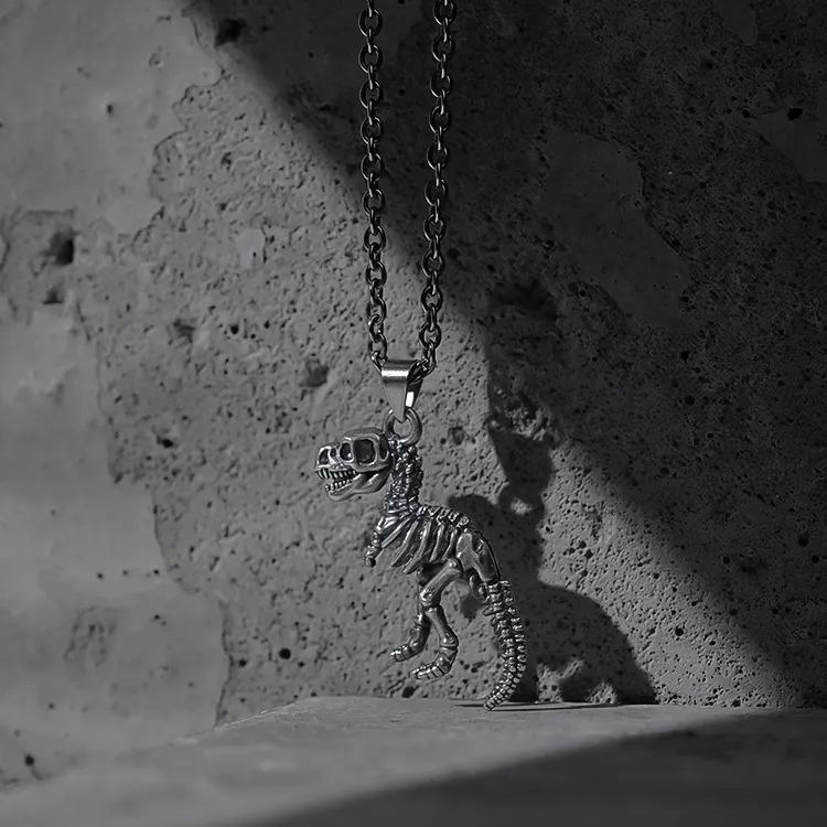 Silver Prehistoric Power necklace with dinosaur skeleton pendant on concrete