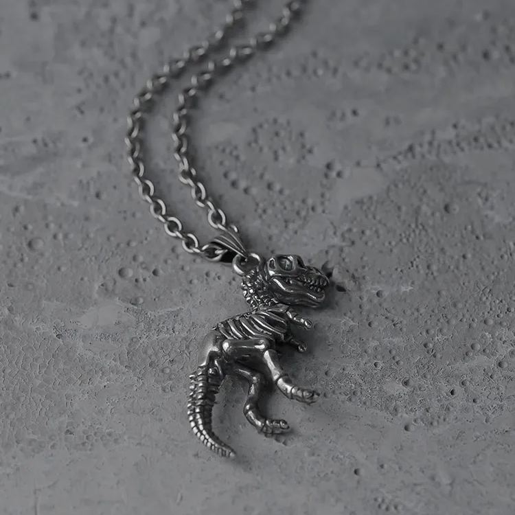 Silver Prehistoric Power necklace shown coiled beside dinosaur skeleton pendant
