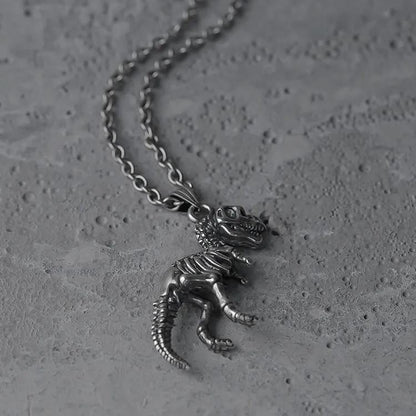 Silver Prehistoric Power necklace shown coiled beside dinosaur skeleton pendant