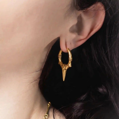 Model wearing gold Primal Blade Earrings with sharp dagger hoop silhouette