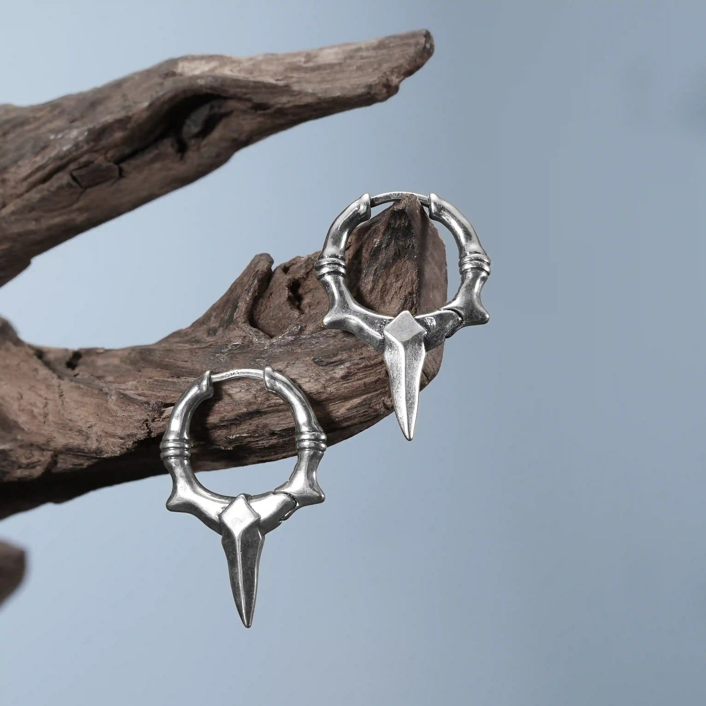 Silver Primal Blade Earrings displayed on driftwood with bone-textured blade hoop design