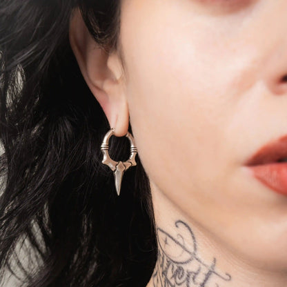 Model wearing silver Primal Blade Earrings with dagger-shaped hoop design and antiqued brass finish