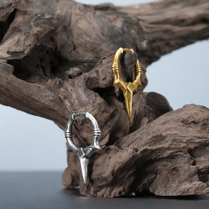 Primal Blade Earrings in silver and gold displayed on weathered wood with dark woodland styling