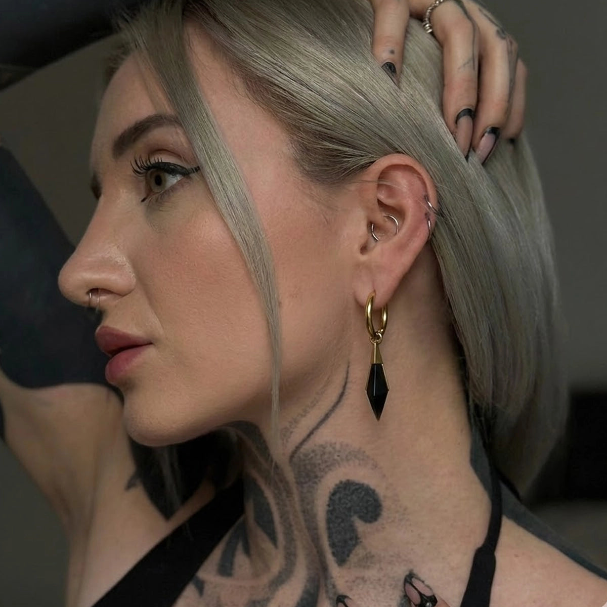 Side view of a model wearing the gold Prism Apex Earrings with black crystal drops and structured gothic styling.