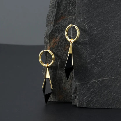 Gold Prism Apex Earrings displayed on a dark stone surface, featuring faceted black crystal drops, polished hoops, and prism-inspired design.