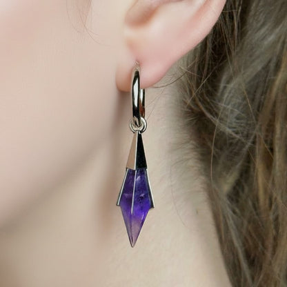 Model wearing the silver Prism Apex Earrings with faceted amethyst crystal drops and polished hoop design.