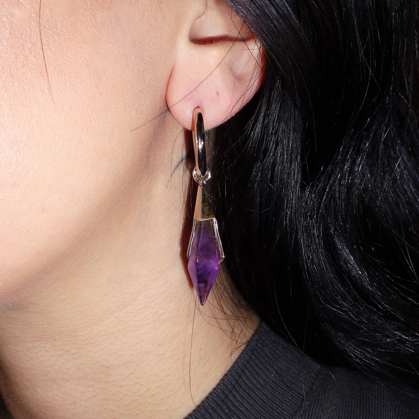 Side view of a model wearing the silver Prism Apex Earrings with purple crystal drops and clean geometric styling.