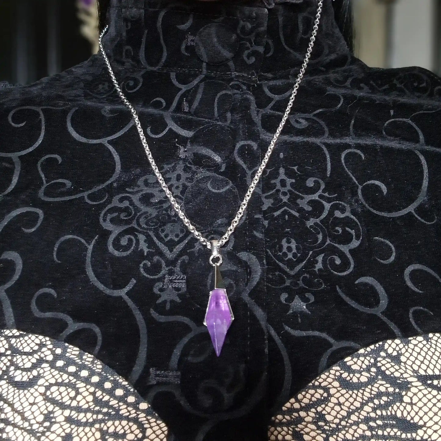 Silver-tone Prism Apex Necklace with a purple crystal pendant displayed on a black patterned jewelry bust.